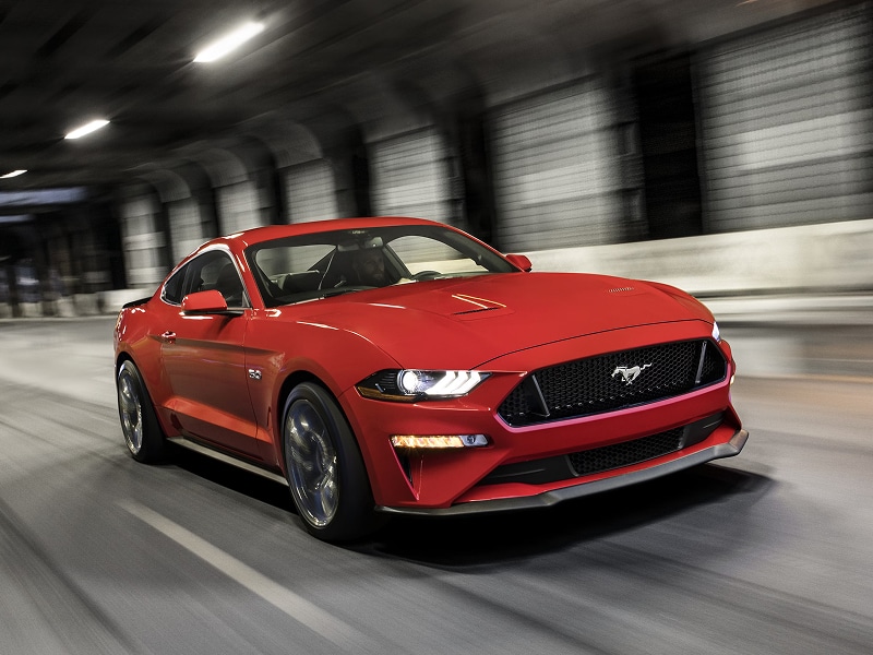 Red sports car driving through a dimly lit tunnel, showcasing its sleek design and dynamic movement.