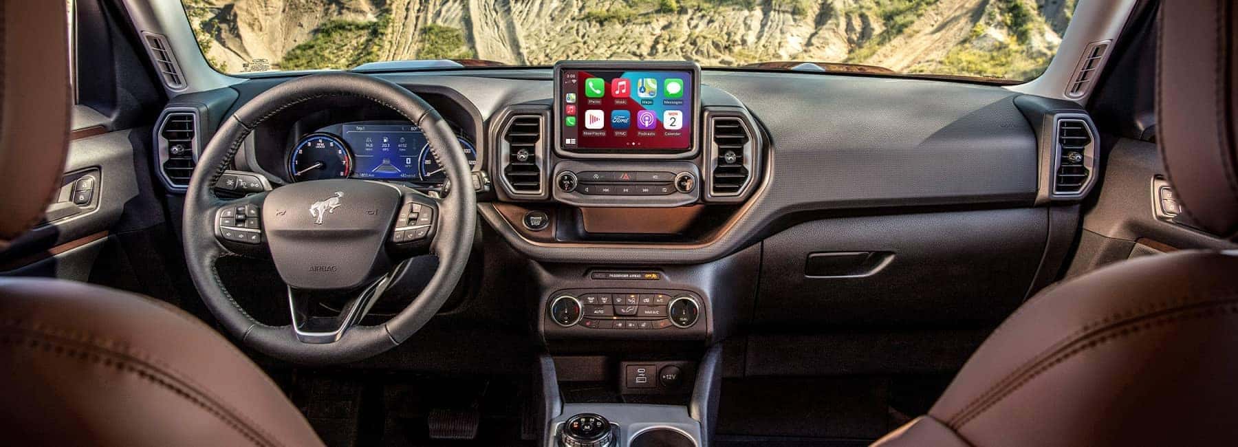 Car interior featuring a modern dashboard, steering wheel, and touchscreen display with app icons.