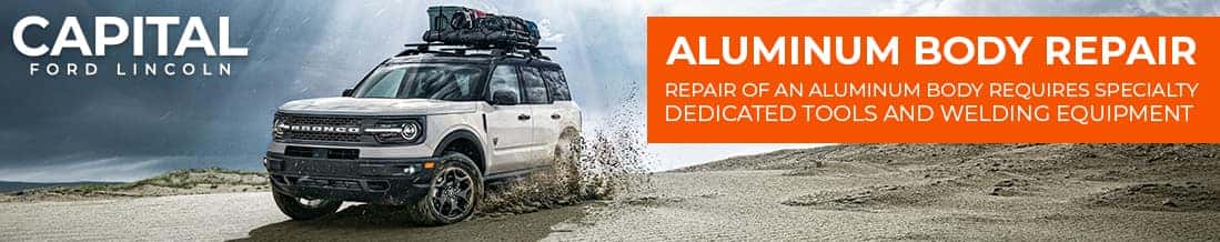Ford SUV driving on sand with text promoting aluminum body repair services at Capital Ford Lincoln.