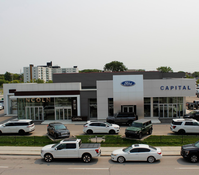 Car dealership featuring Lincoln and Ford signage, with several vehicles parked in front.