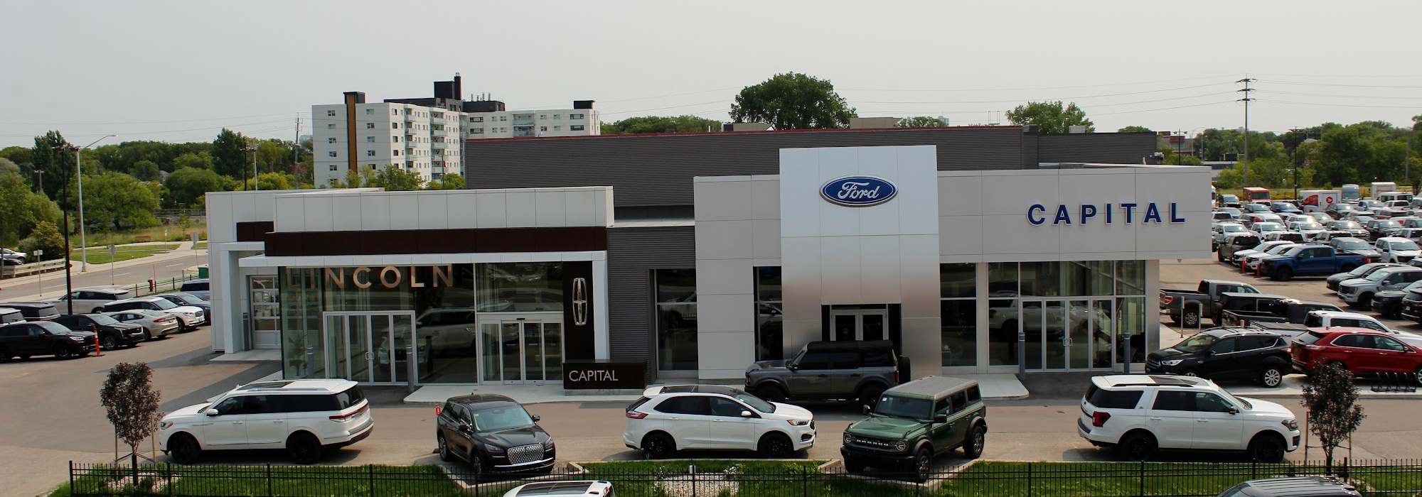 Car dealership featuring Ford and Lincoln brands with a parking lot full of vehicles.