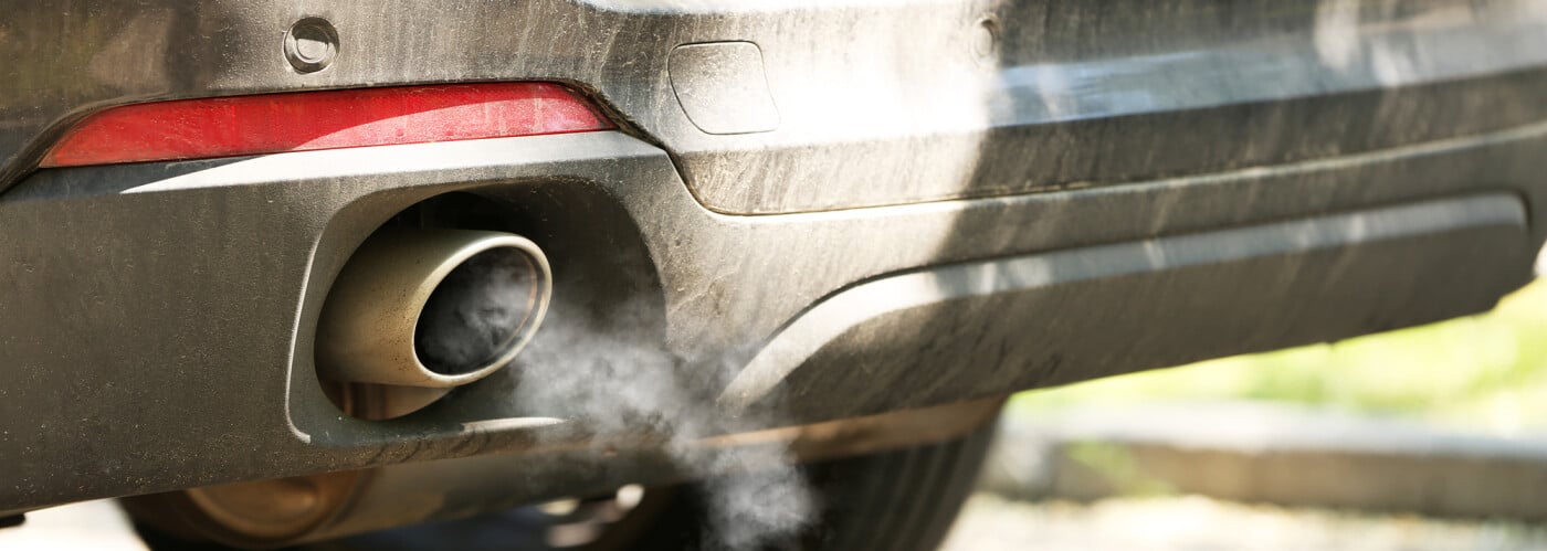 Close-up of a car exhaust emitting fumes, highlighting vehicle emissions and environmental impact.