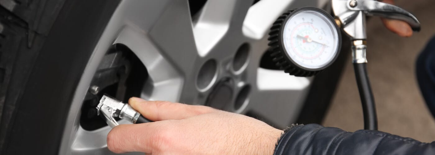 Hand checking tire pressure with a gauge on a car tire. Auto maintenance concept.