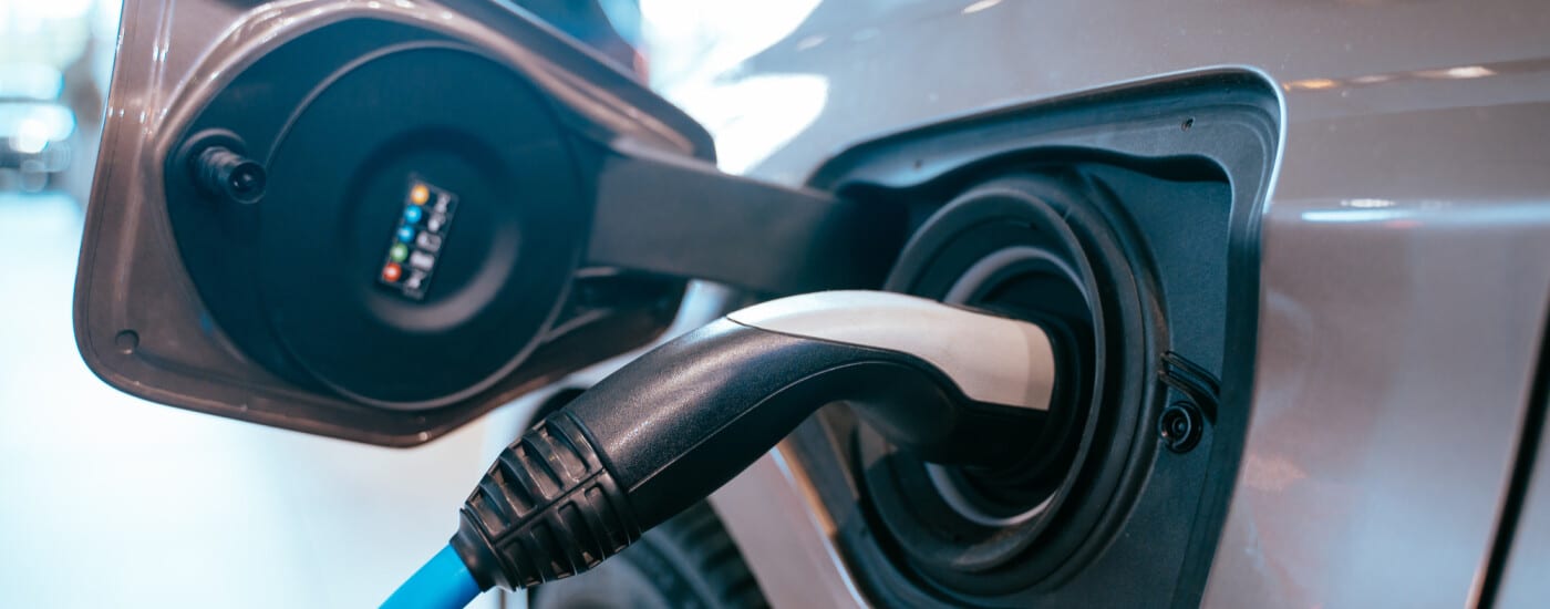 Electric vehicle charging port with a blue cable plugged in.