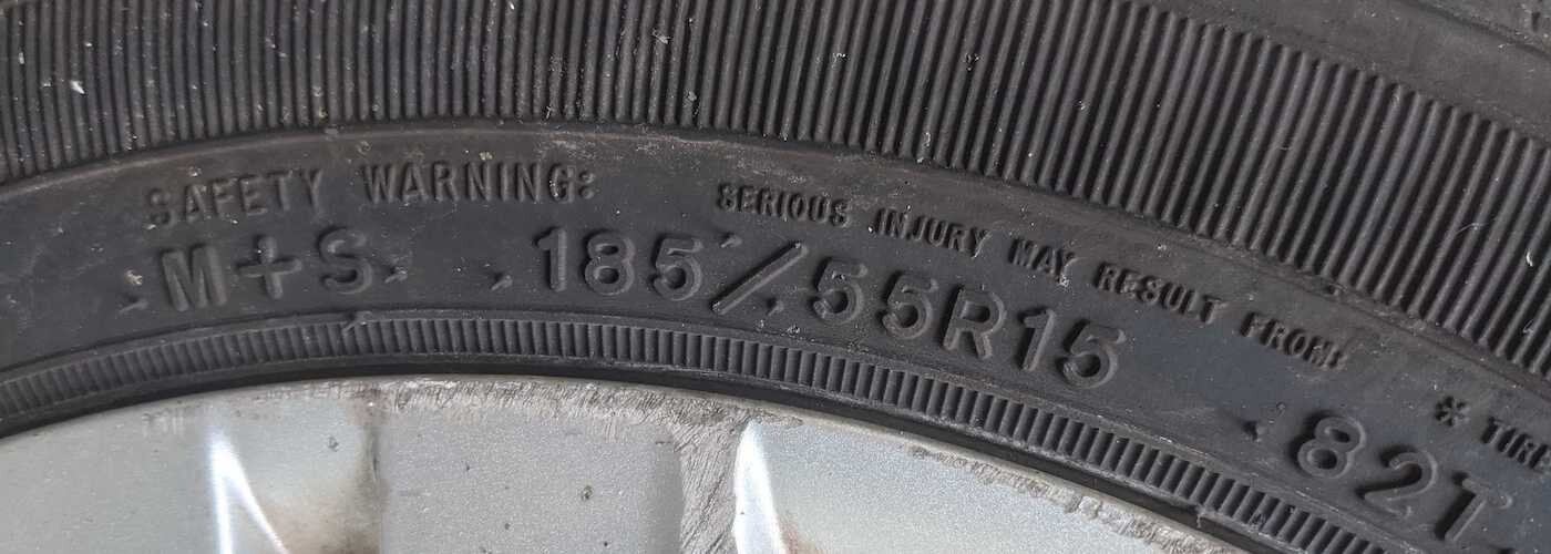 Close-up of a tire displaying size 185/55R15 and a safety warning about serious injury.
